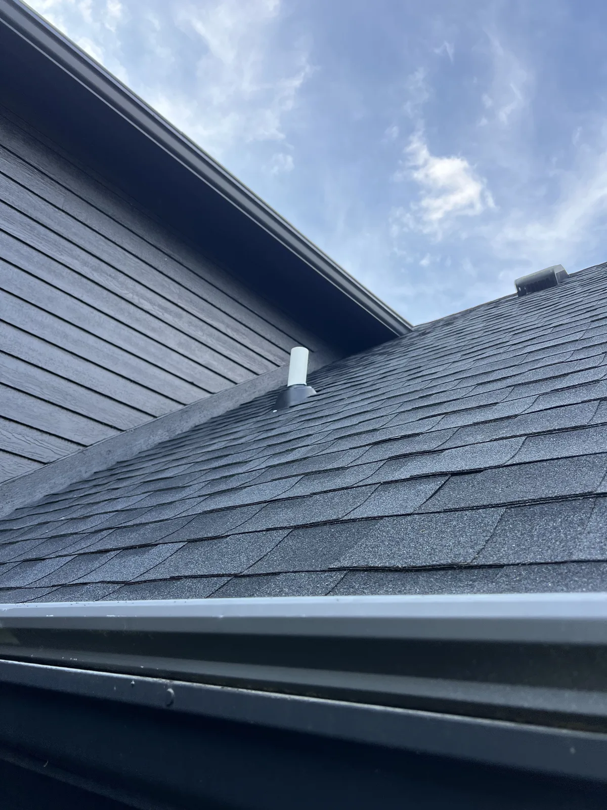 White vent pipe extending through a shingled roof
